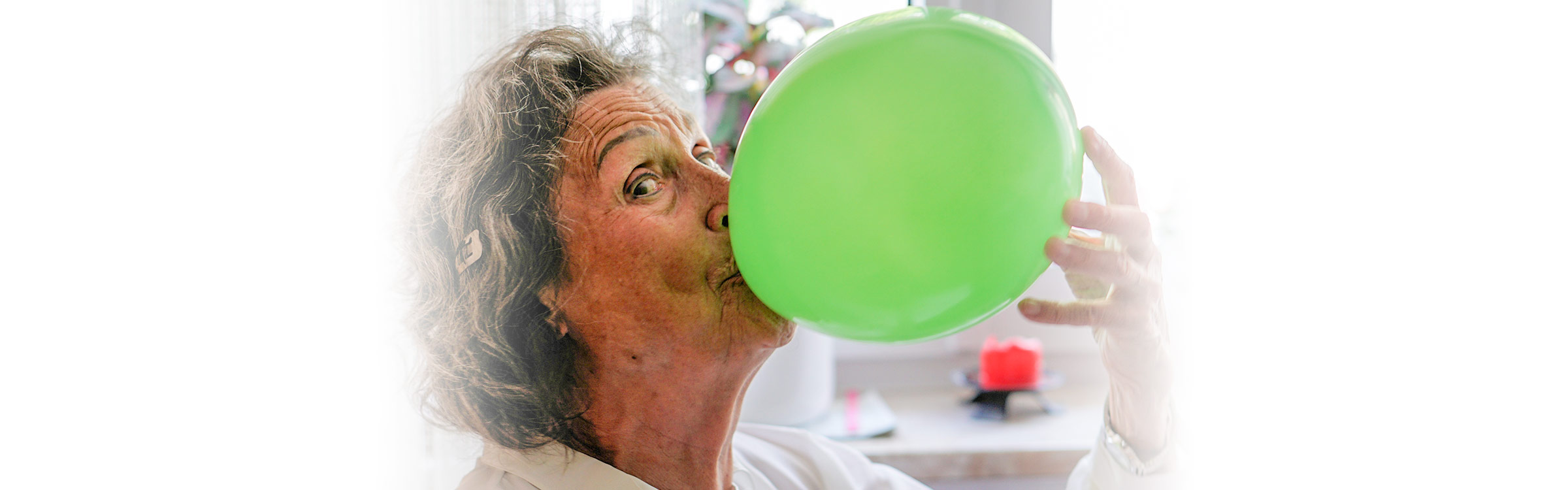 Patientin von Bunz mobile Physio trainiert zu Hause Ihre Atemmuskulatur mithilfe eines Luftballons.